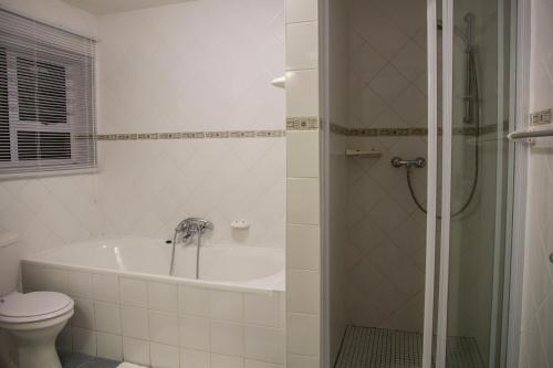 a bathroom with a tub and a toilet and a shower at Sand & Sea Holiday Home in Swakopmund