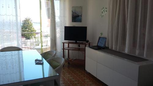 a living room with a television and a table with a laptop at Casa Roby 120 mt Beach in Fontane Bianche