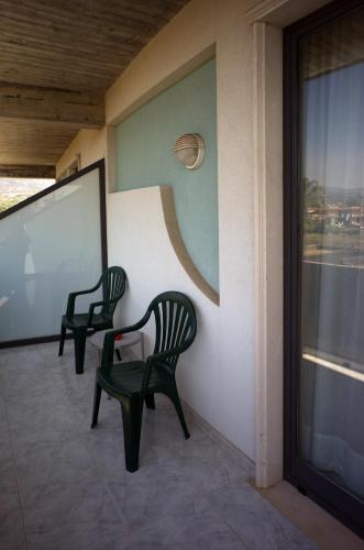 two green chairs sitting on the side of a building at Atlantis Palace Hotel in Mascali