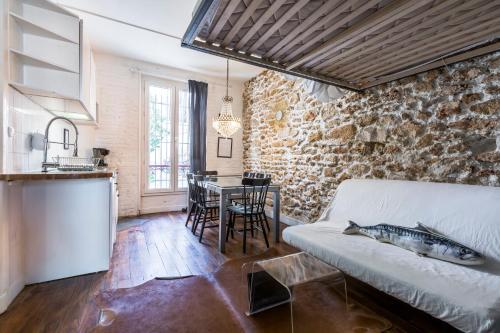 Cosy 40m² near MONTMARTRE في باريس: مطبخ وغرفة معيشة مع أريكة وطاولة