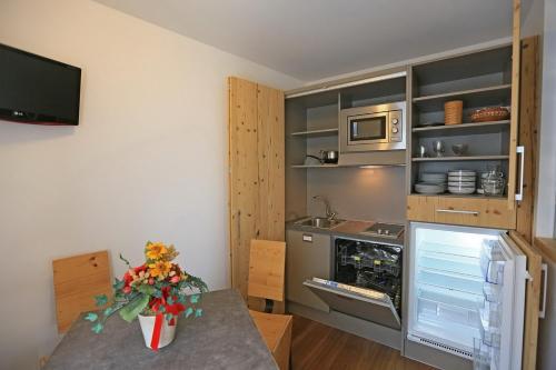 a kitchen with a table with a vase of flowers on it at Hotel San Giovanni in Vigo di Fassa