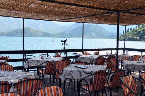 a restaurant with tables and chairs with a view of the water at Apartmani Konoba Starčevo in Virpazar