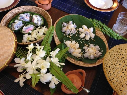 a table with three plates of food and flowers on it at SSIP Boutique Dhevej Bangkok in Bangkok