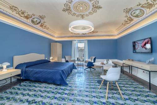 een blauwe slaapkamer met een bed en tafels en stoelen bij Appartamenti Vista Duomo - Ibla - Pomelia in Ragusa