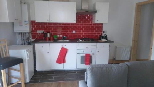 a kitchen with white cabinets and a red brick wall at Murrevagh Mealog in Tooreen