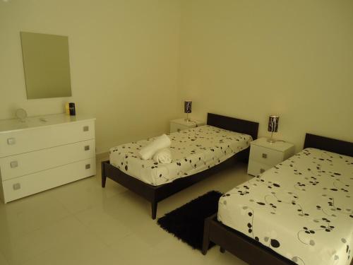 a bedroom with two beds and a dresser at Shamrock Flats in Mellieħa