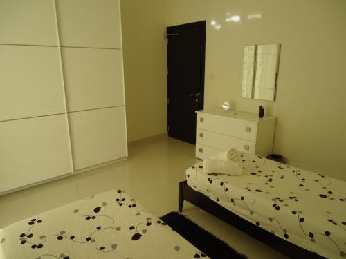 a bedroom with two beds and a dresser and a mirror at Shamrock Flats in Mellieħa