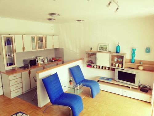 Sala de estar con 2 sillas azules y TV en Apartment Lent en Maribor
