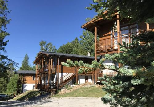 a large wooden house with a balcony and stairs at Apartmány Planina Predná Hora in Predná Hora