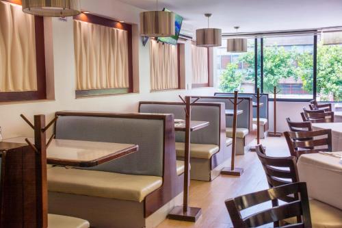 a dining room with chairs and tables and windows at Hotel Castropol in Mexico City