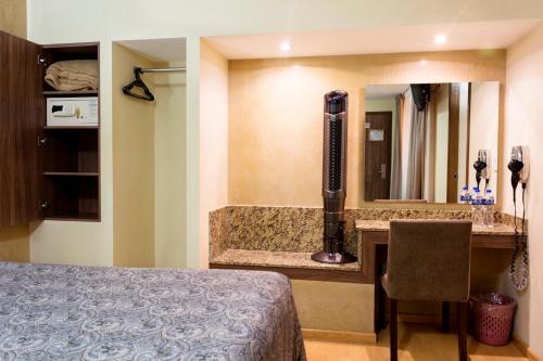a hotel room with a bed and a bathroom with a sink at Hotel Castropol in Mexico City