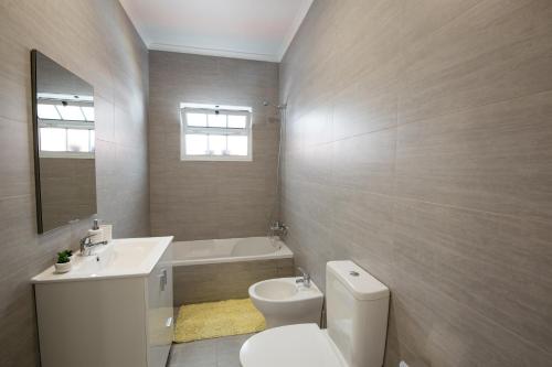 a bathroom with a toilet and a sink and a mirror at Seaside Azores Villa with natural pool, terrace & barbecue in Capelas