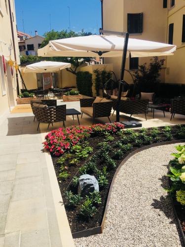 a patio with tables and umbrellas and flowers at Santa Croce Boutique Hotel in Venice