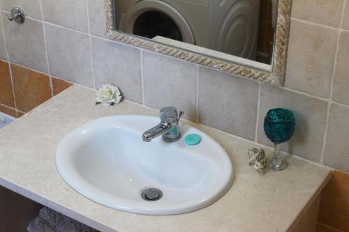 un lavabo blanc dans une salle de bain avec un miroir dans l'établissement Villa Marikami, à Kamilárion