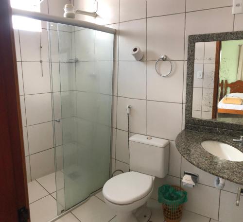 a bathroom with a toilet and a sink and a mirror at Epílogo Palace Hotel in Rio Branco