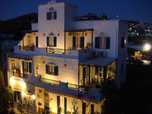 a large white building with lights on it at night at Boussetil Rooms CapAnMat in Tinos Town