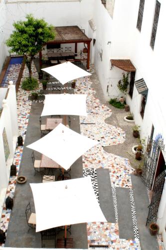an empty courtyard with tables and white umbrellas at Hotel Blanco Riad in Tetouan