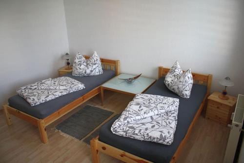 um quarto com duas camas com almofadas e uma mesa em An der Alten Schule 2 em Oelsnitz