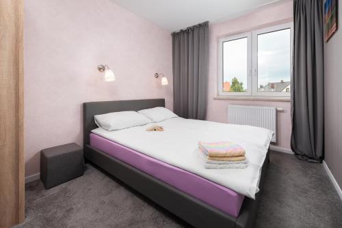 a bedroom with a large bed with purple and white sheets at Pastelowe mieszkanie in Puck