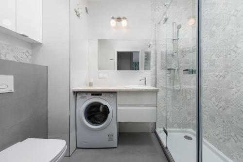 a bathroom with a washing machine and a shower at Pastelowe mieszkanie in Puck