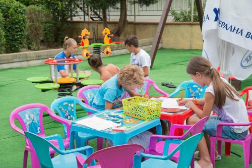 a group of children sitting at tables in a play yard at Aparthotel Hotel Prestige City II in Primorsko