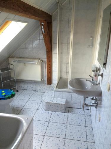 Baño blanco con lavabo y bañera en Schorfheider Ferienwohnung, en Eberswalde-Finow