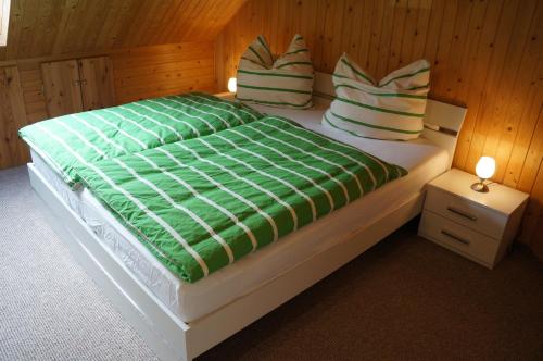 1 dormitorio con 1 cama con edredón y almohadas verdes en Schorfheider Ferienwohnung, en Eberswalde-Finow