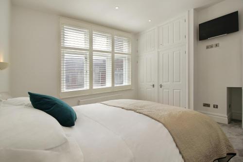 a white bedroom with a bed and a flat screen tv at Macatsim Seaview Sunset in Margate