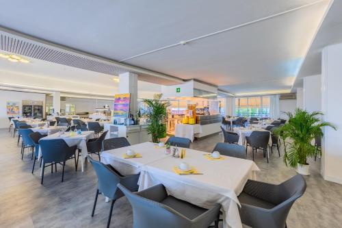 a restaurant with white tables and blue chairs at Marina Palace Hotel 4 stelle S in Caorle