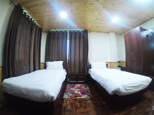 2 łóżka w niewielkim pokoju z drewnianymi ścianami w obiekcie Temi Sarika Homestay w mieście Damthang