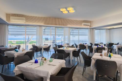 a restaurant with white tables and chairs and windows at Marina Palace Hotel 4 stelle S in Caorle