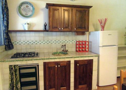 uma cozinha com armários de madeira e um frigorífico branco em Studio Apartment with garden and free parking em Giardini Naxos