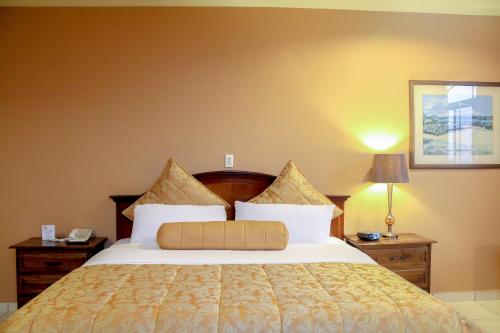a bedroom with a large bed with white pillows at Hotel Monteolivos in San Pedro Sula