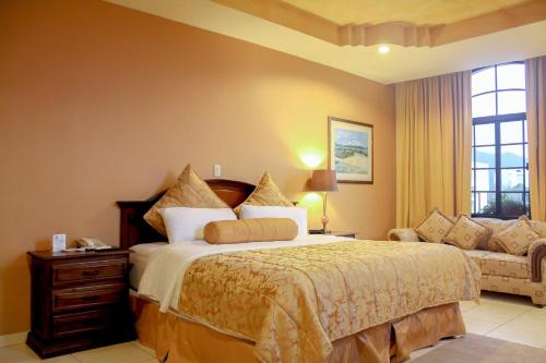 a bedroom with a large bed and a couch at Hotel Monteolivos in San Pedro Sula
