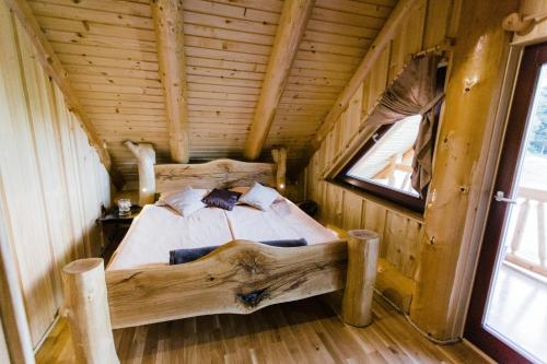 uma cama num chalé de madeira com uma janela em Forest Glade Cottage - Koča na jasi em Rečica ob Savinji
