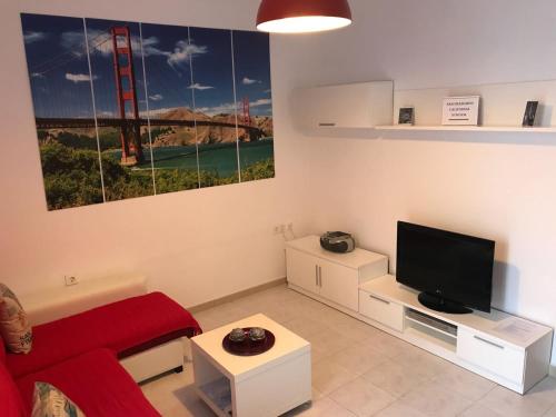 ein Wohnzimmer mit einem roten Sofa und einem Fernseher in der Unterkunft San Francisco's House in Medina-Sidonia