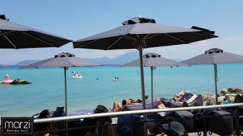 a group of people sitting on the beach under umbrellas at Marzi Boutique Hotel in Nerátza