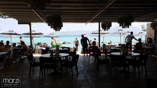 a restaurant with people sitting at tables on the beach at Marzi Boutique Hotel in Nerátza