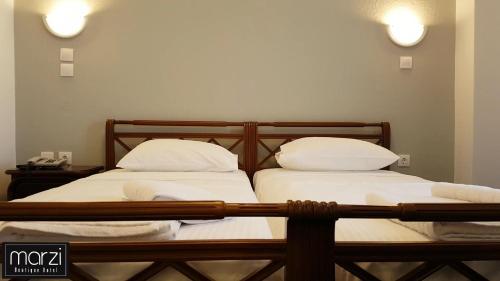 two beds in a room with white sheets and pillows at Marzi Boutique Hotel in Nerátza