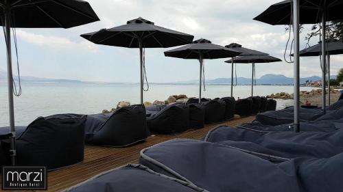 a row of blue chairs with umbrellas on the beach at Marzi Boutique Hotel in Nerátza