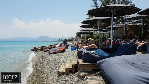a group of people sitting on a beach with umbrellas at Marzi Boutique Hotel in Nerátza