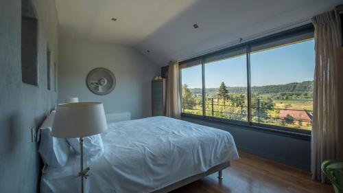 a bedroom with a bed and a large window at Maison Anne Fouquet in La Roque-Gageac