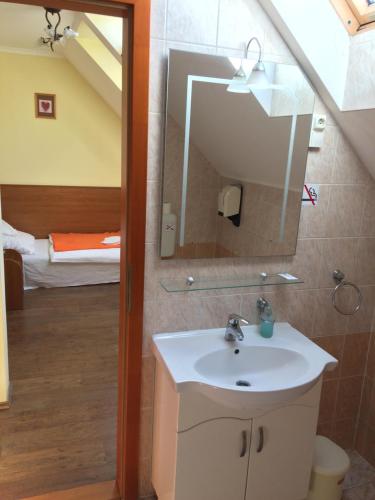 a bathroom with a sink and a mirror and a bed at Natural Panzió in Győr