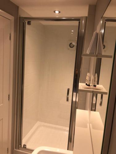 una ducha con una puerta de cristal junto a un lavabo en No 3 New Inn Apartments, en Newark-on-Trent