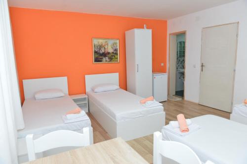 a room with two beds and an orange wall at Rooms Ela Ela in Prekodolce