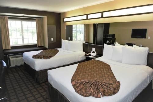 a hotel room with two beds and a television at Microtel Inn & Suites by Wyndham Jacksonville Airport in Jacksonville