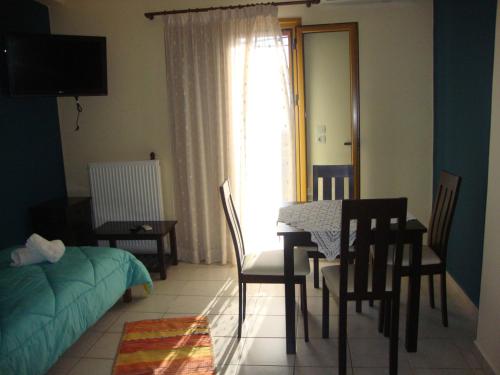 een woonkamer met een tafel en stoelen en een slaapkamer bij Kafiona Guesthouse in Pirgos Dhirou