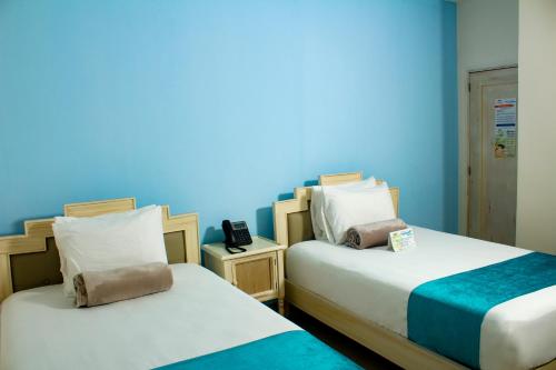 two beds in a room with a blue wall at Hotel Med Barranquilla Centro in Barranquilla