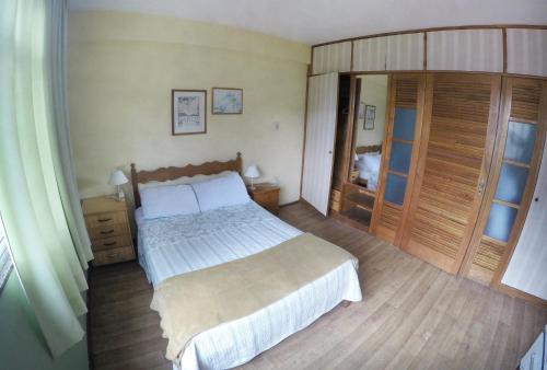 a bedroom with a large bed and wooden floors at Apartamento no Centro de Friburgo in Nova Friburgo