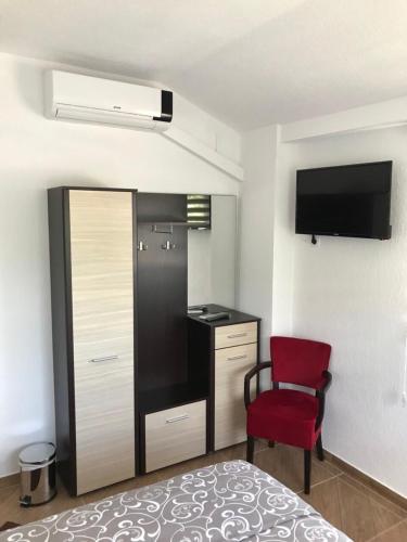 a small room with a bed and a red chair at Becar Pyramid Rooms in Visoko